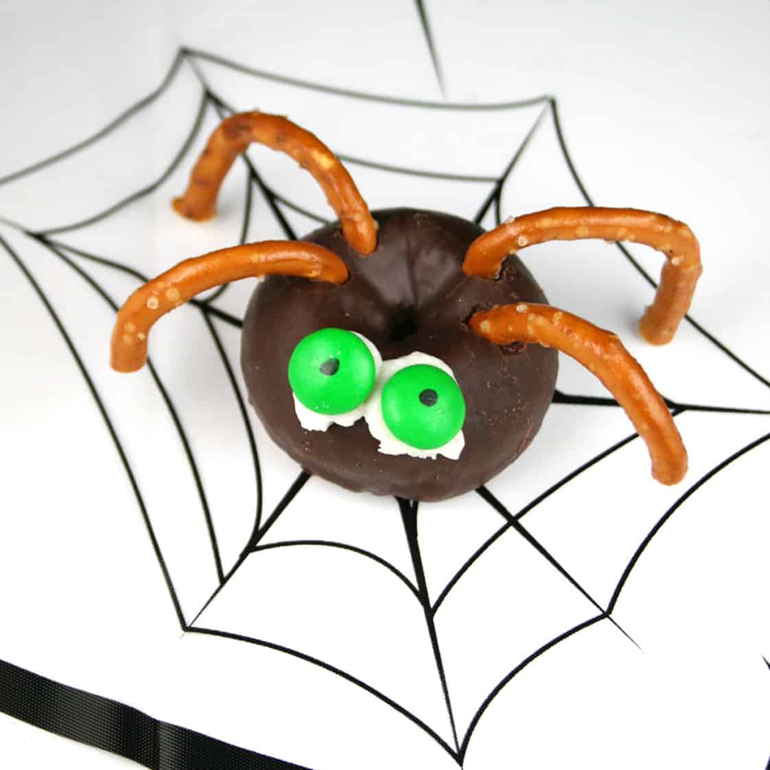 Mini chocolate donut with candy eyes and pretzel legs for Halloween.