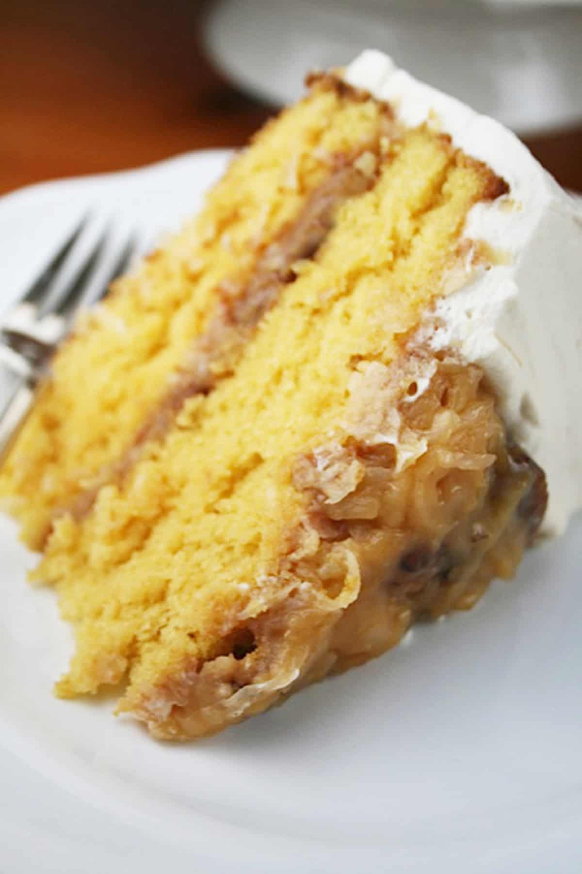 Slice of coconut pecan butterscotch cake on a white plate.