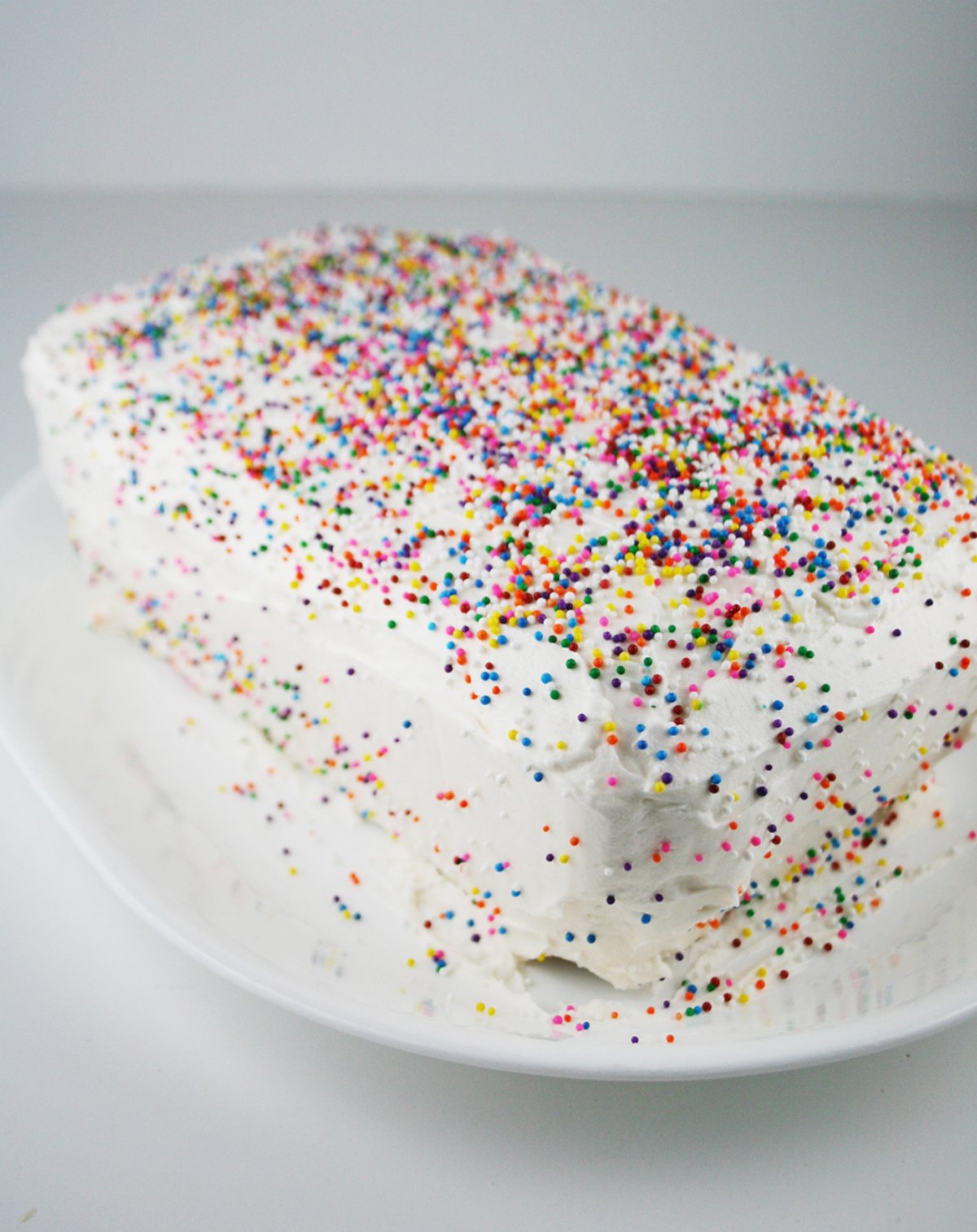 Homemade cake frosted with white buttercream and topped with sprinkles.