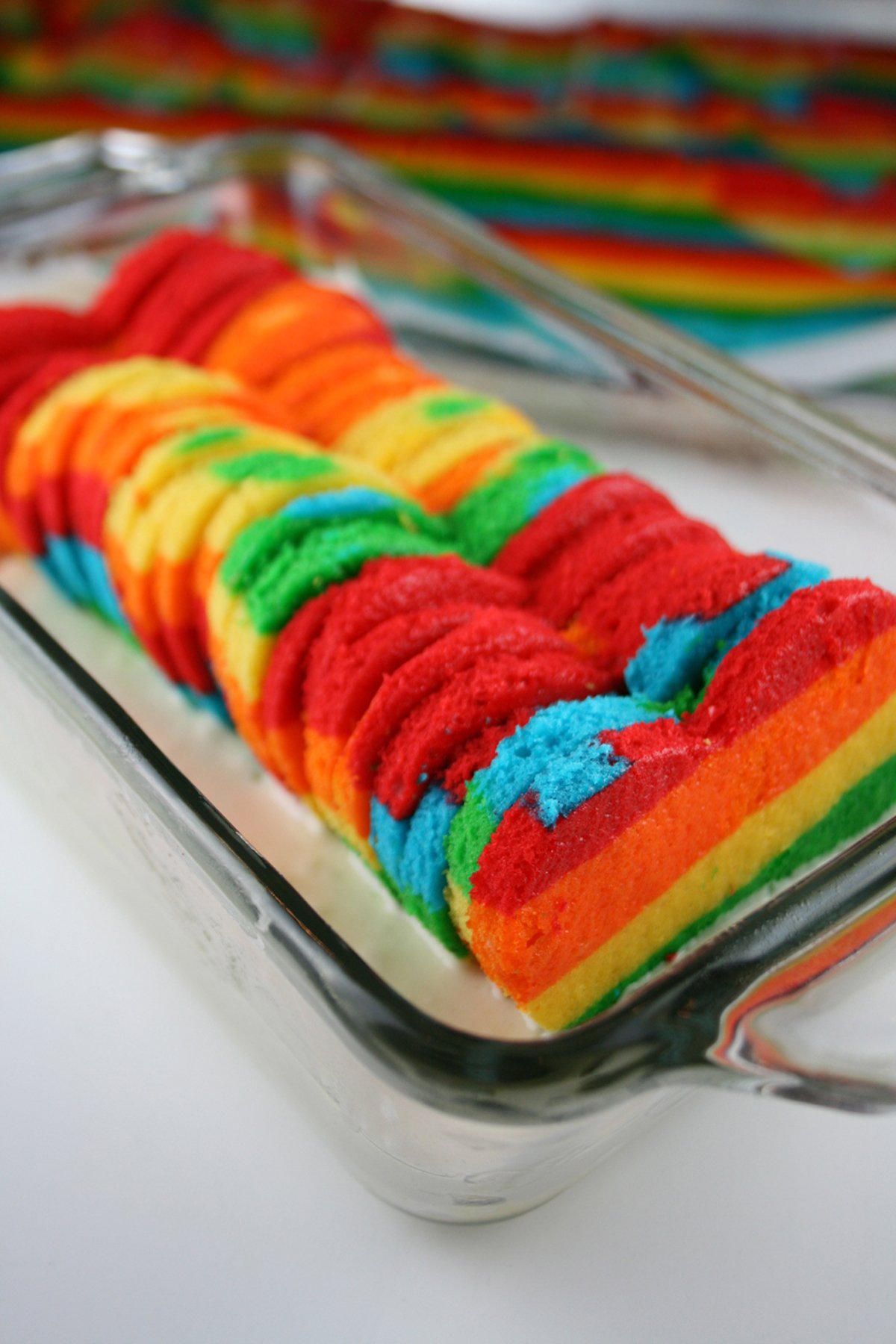 Heart shaped rainbow cake in a glass loaf pan.