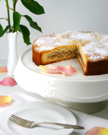 Almond filled cookie cake on white cake stand with a piece of cake missing.