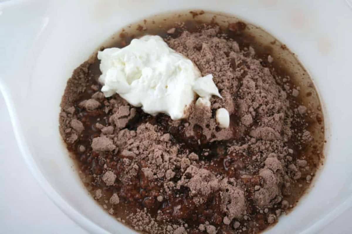 brownie mix with water added and dollop of whipped cream in a white bowl. 