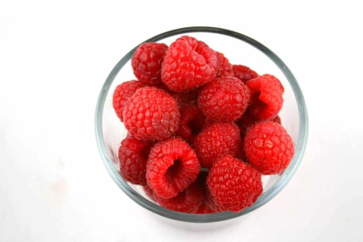 a clear bowl containing raspberries