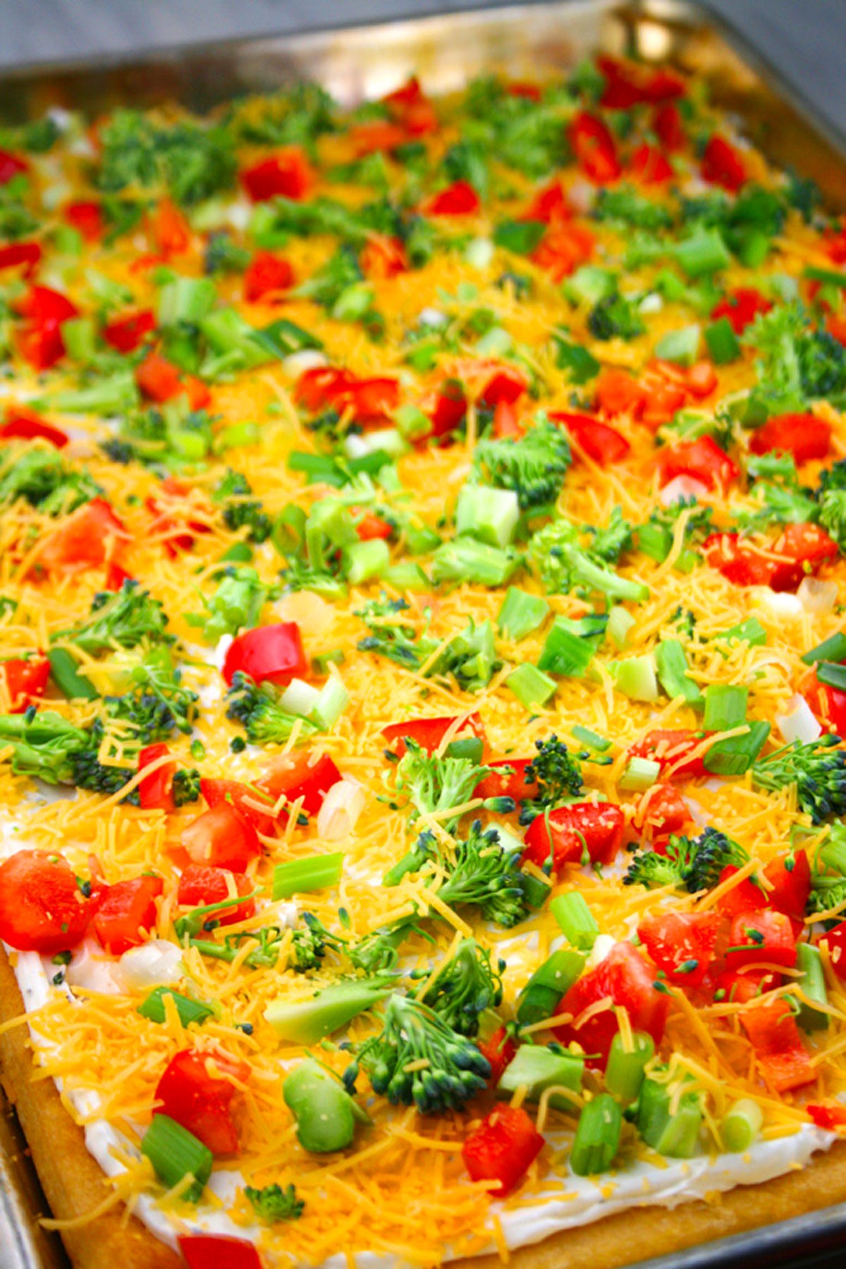 Colorful veggies on top of cold veggie pizza.