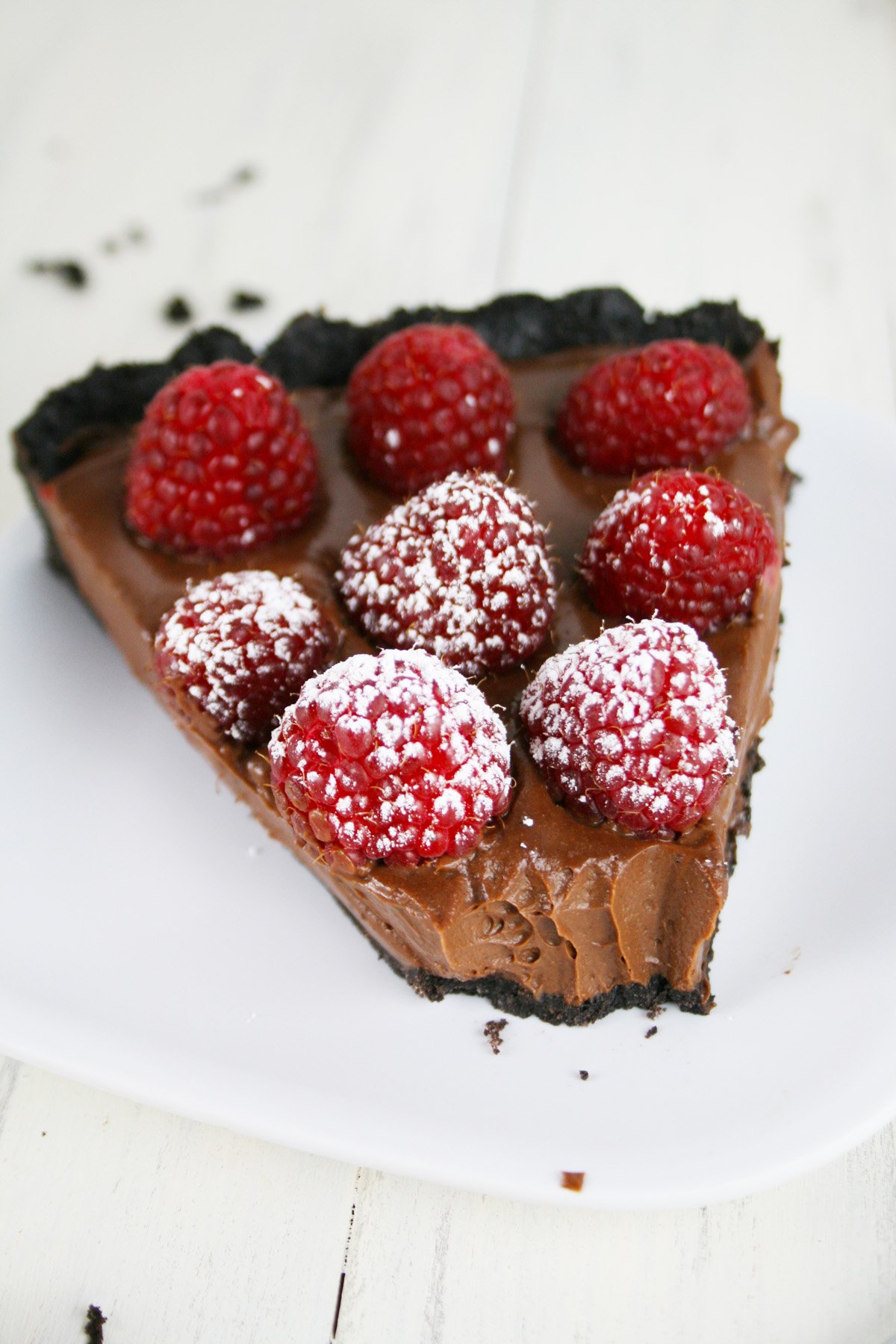 Slice of chocolate pie with raspberries on top.