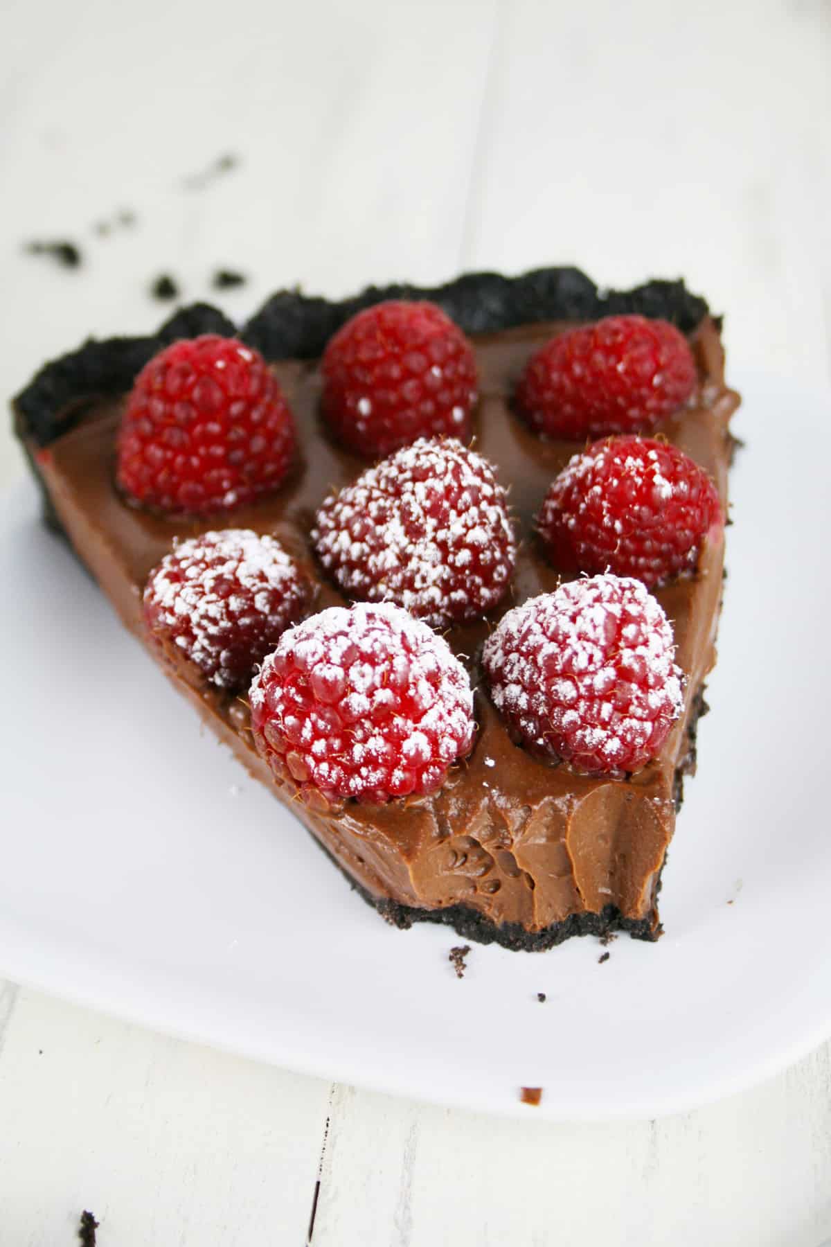 Slice of chocolate pie with raspberries on top.