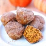 Five mini pumpkin muffins on a white plate.