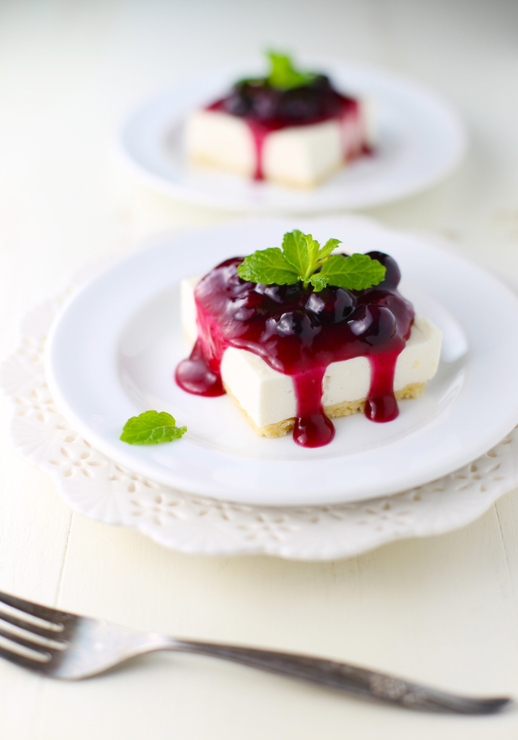 Blueberry cheesecake bars on white plates.