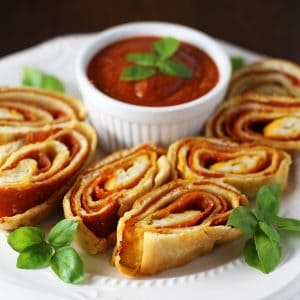 Easy Stromboli sliced on a white plate with sauce and fresh basil.