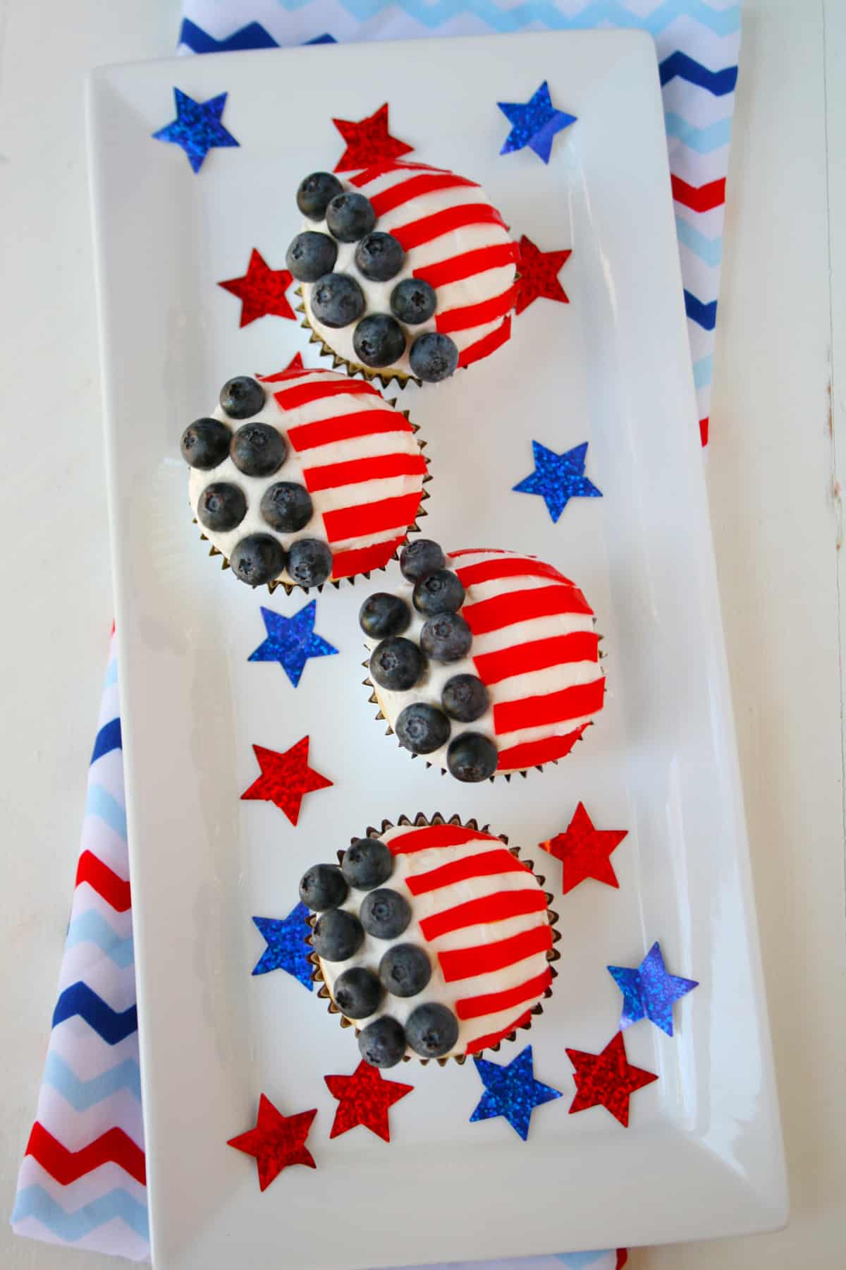 White rectangle plate with four American flag cupcakes on the plate.