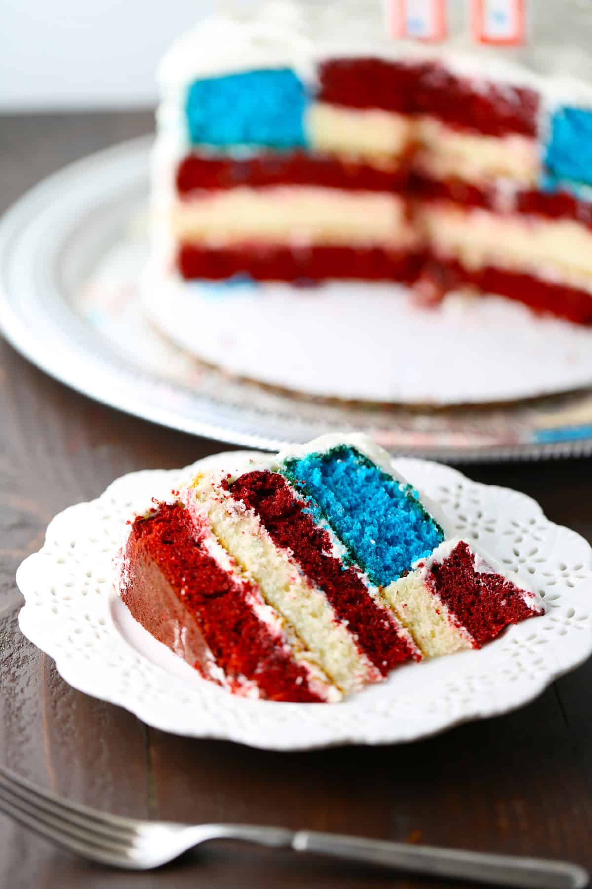 Sliced American flag surprise inside cake on a white plate.