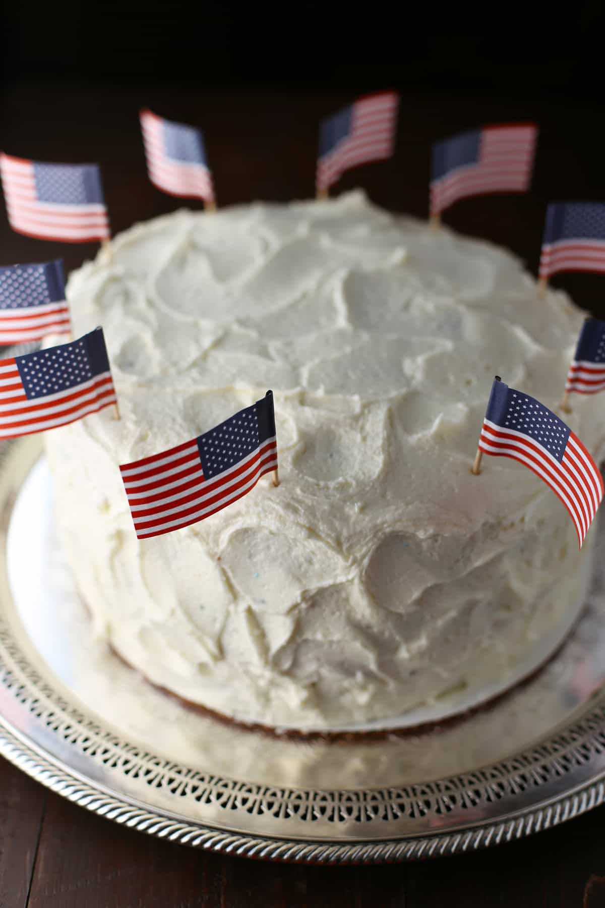 Frosted flag cake with toothpick flags on top.