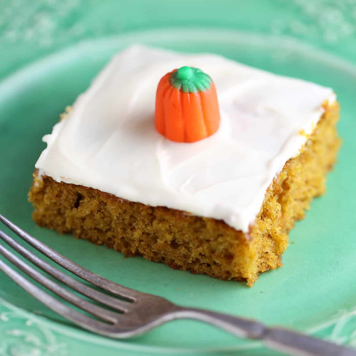 One pumpkin bar on green plate with fork on side.