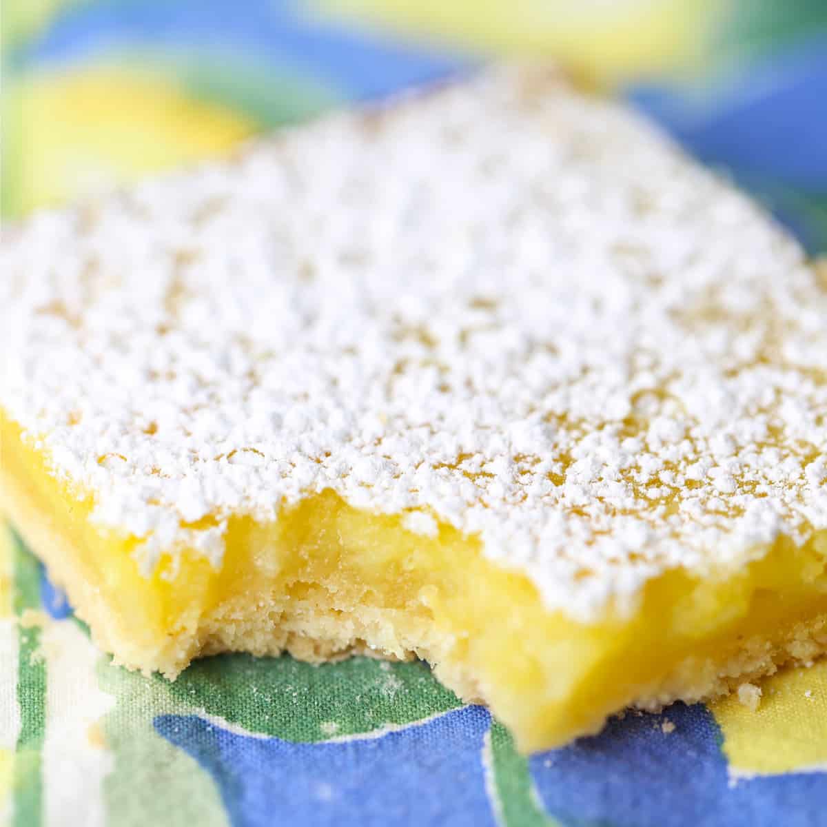 One lemon bar on napkin with a bite taken out