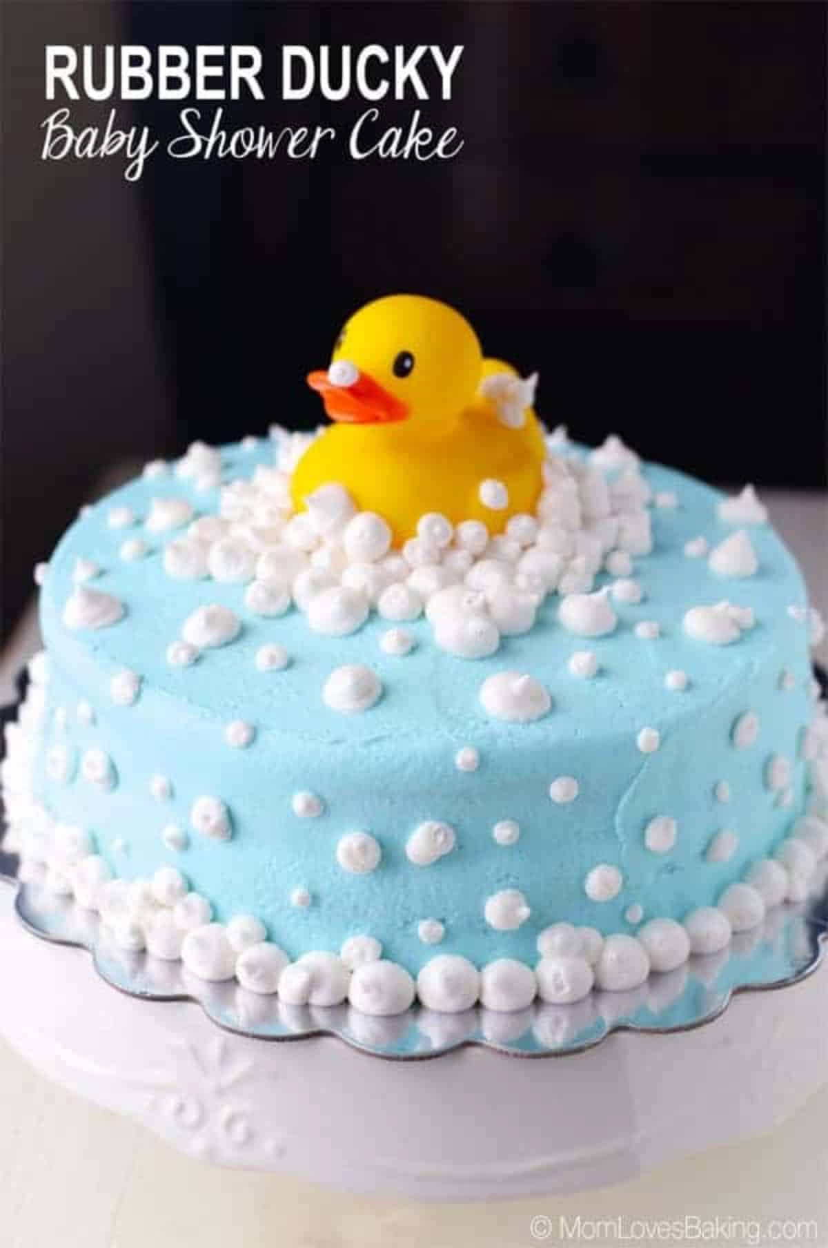 rubber ducky on stop of a blue cake with white frosting for bubbles