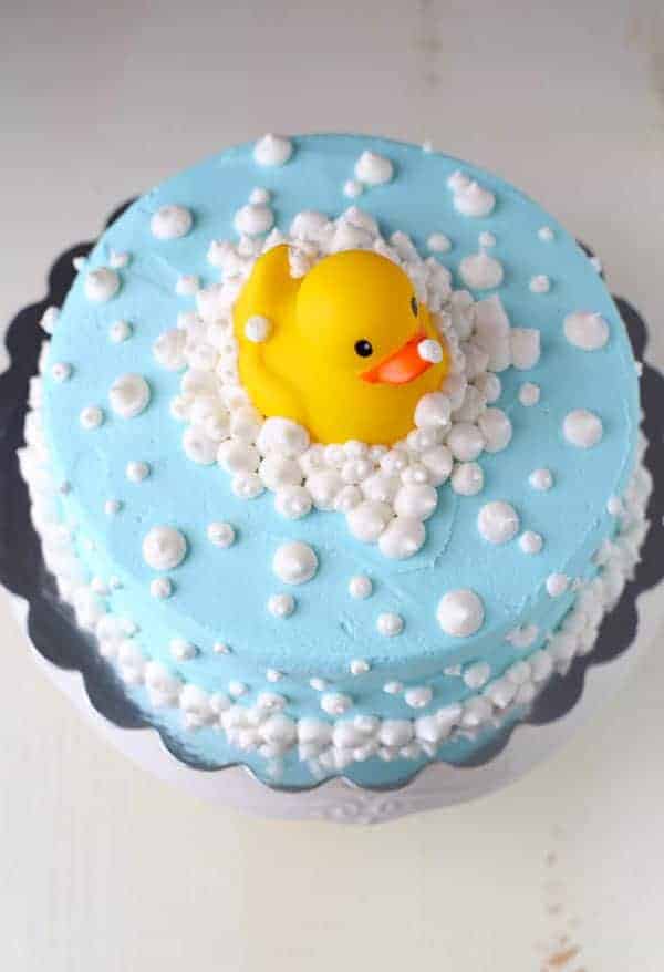 Blue frosting on round cake with white frosting bubbles and yellow rubber ducky.