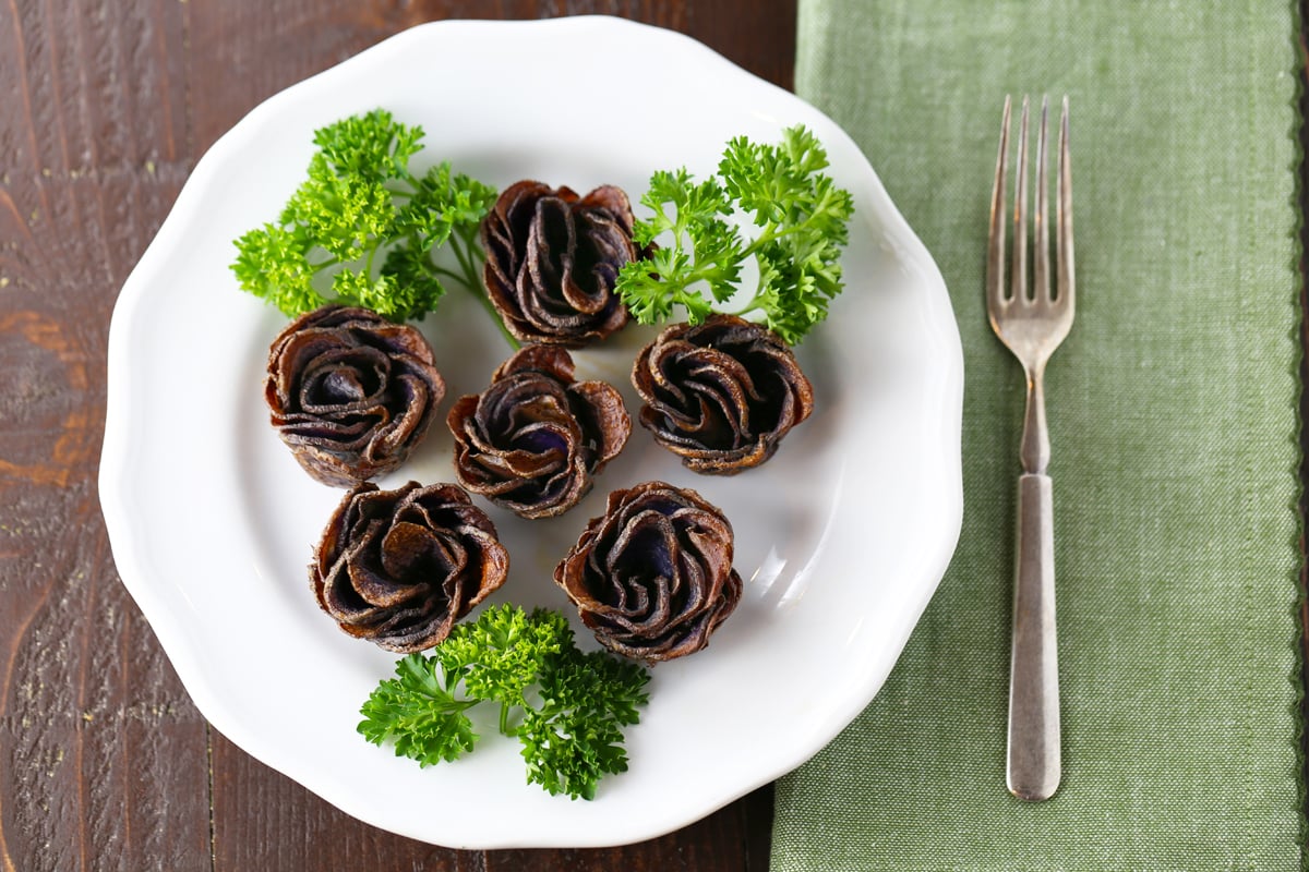 Baked potato roses on a white plate with parsley.