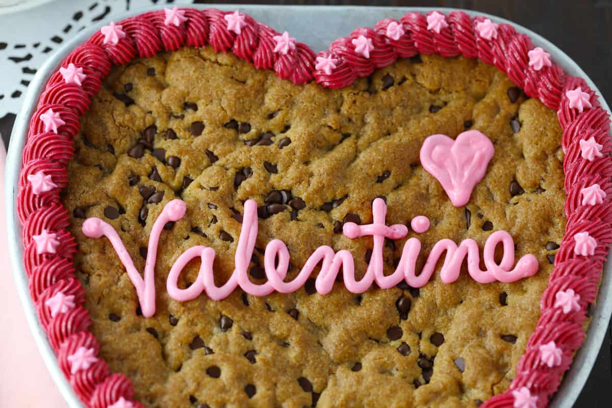 Heart cookie cake with pink buttercream border and the word valentine piped on top.