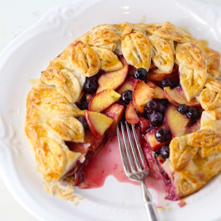 Rustic blueberry galette with pie dough leaves on the edges.