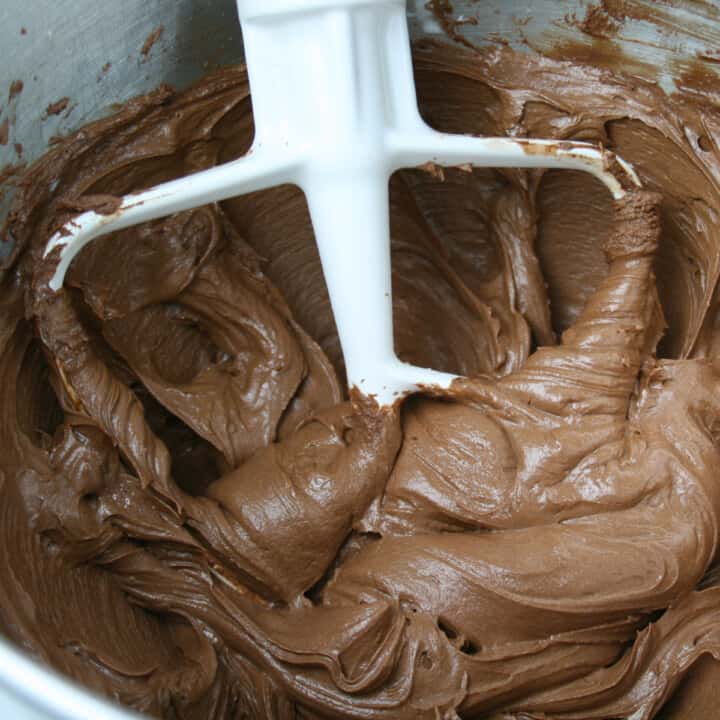 Chocolate frosting in mixing bowl with paddle attachment.