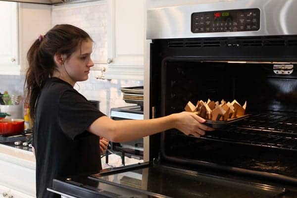 Daughter putting muffins in the oven