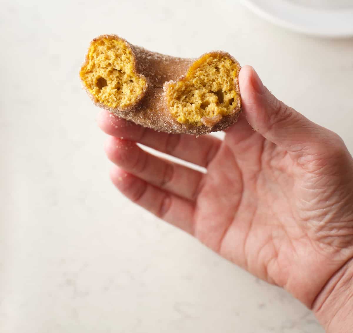 Hand holding a half eaten pumpkin donut.