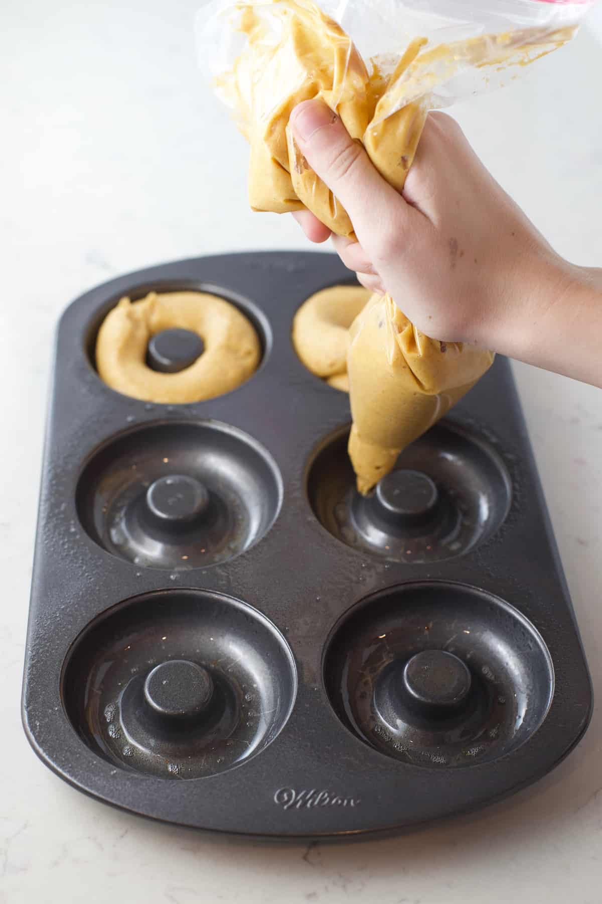 Piping donut batter into a doughnut pan