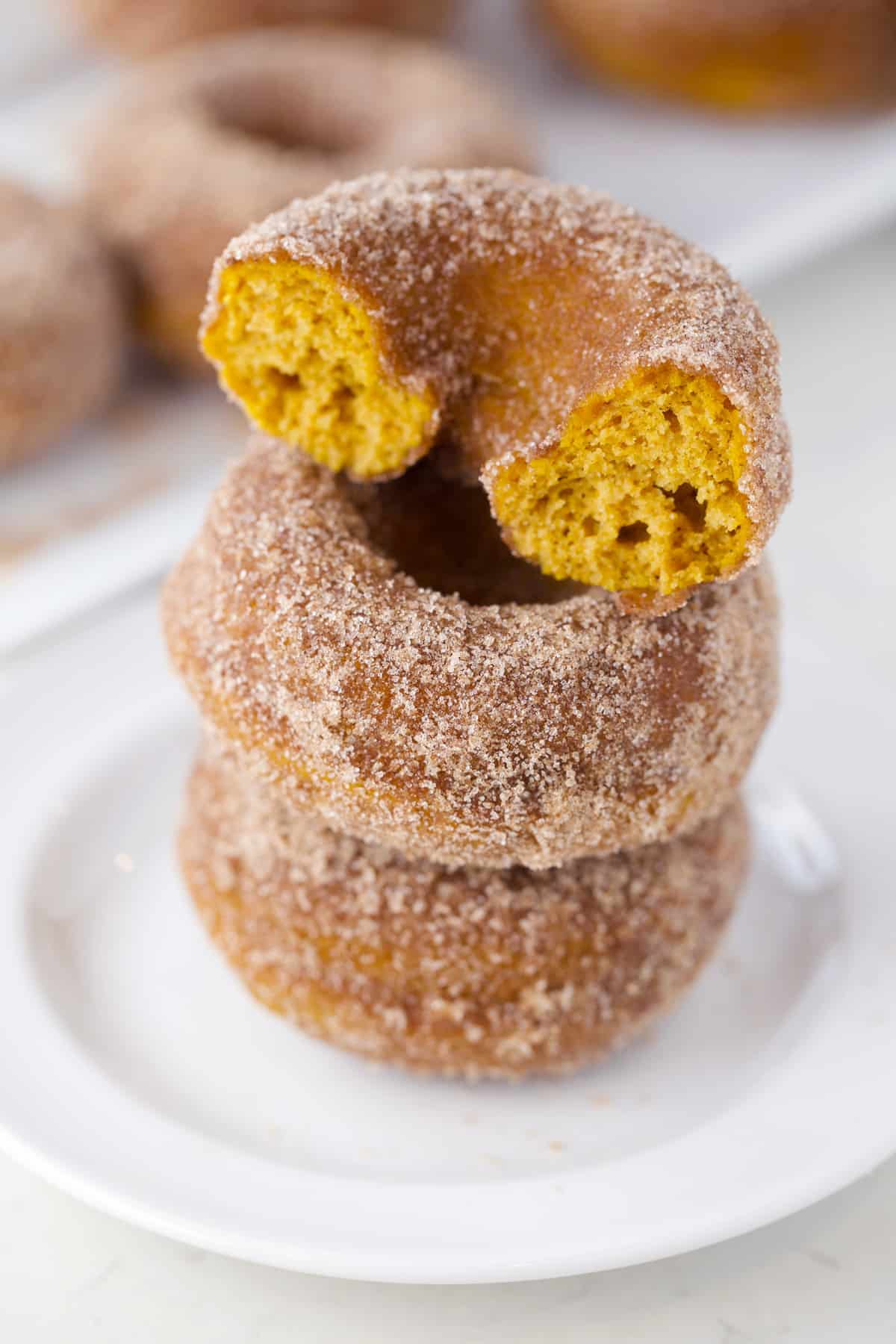 Stack of three baked donuts with top one having a bite.