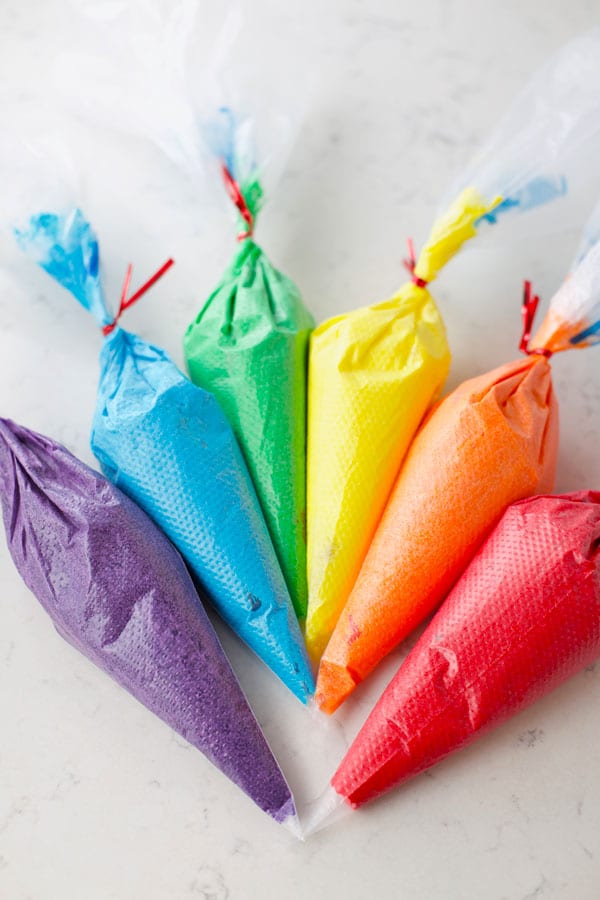 Piping bags full of rainbow colors of frosting