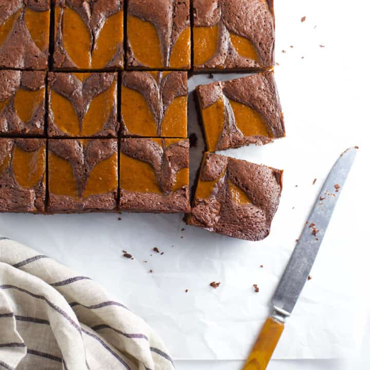 Pumpkin brownies cut into squares with towel on the side.