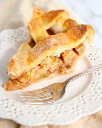 Slice of best ever apple pie on white plate with fork.