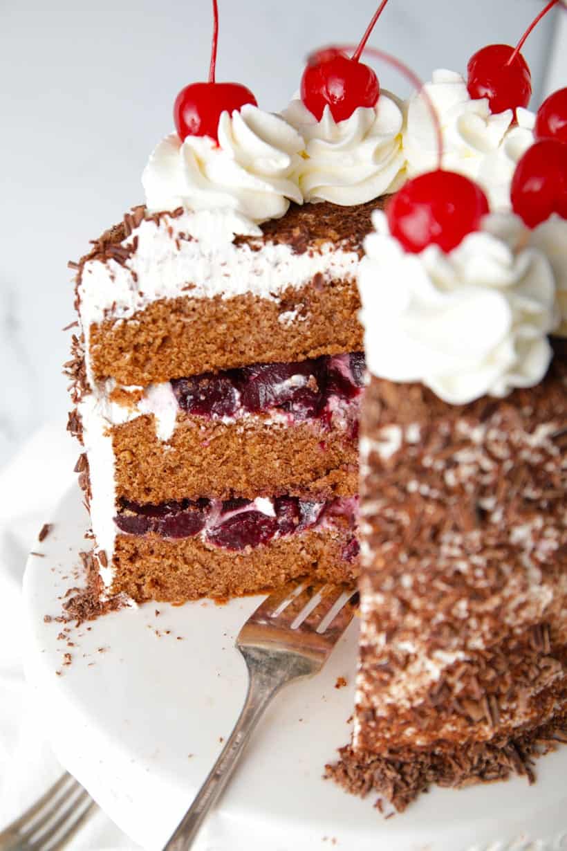 Sliced cake with cherries whipped cream and chocolate shavings cherry brandy