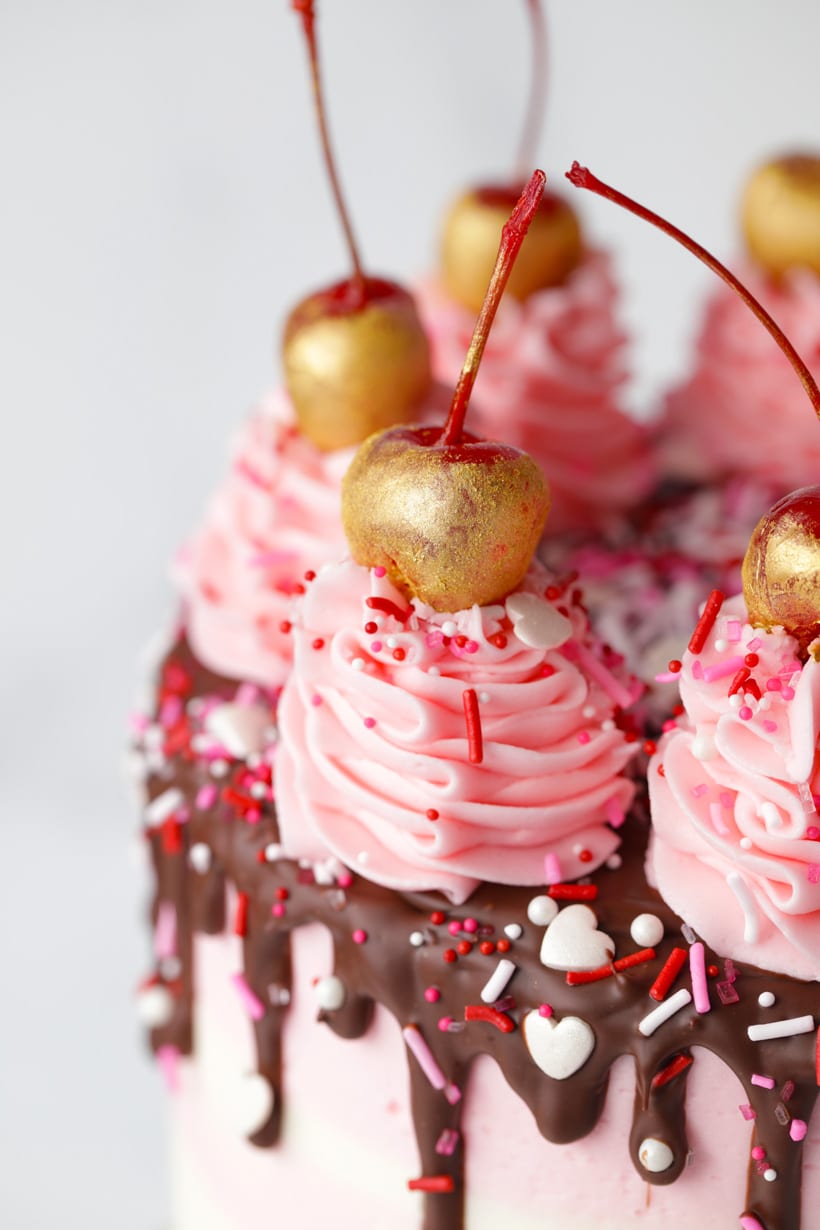 Gold cherries on pink striped buttercream cake