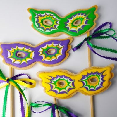 Mardis gras mask cookies on a stick in green purple yellow