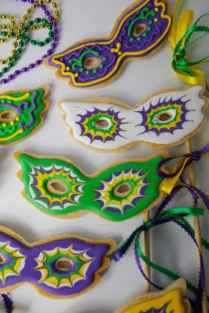 Royal icing decorated mardis gras mask sugar cookies on a stick