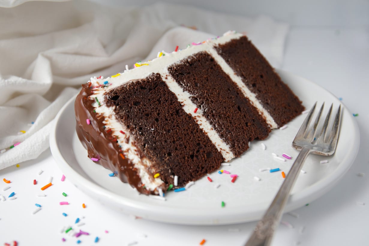 Slice of gluten free chocolate layer cake with vanilla frosting