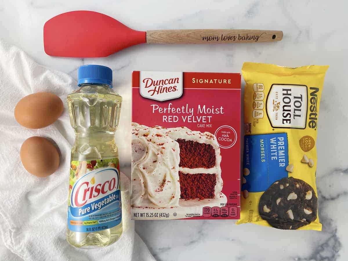 Cookie ingredients laid out on counter, eggs, Crisco oil, cake mix, white chocolate chips.