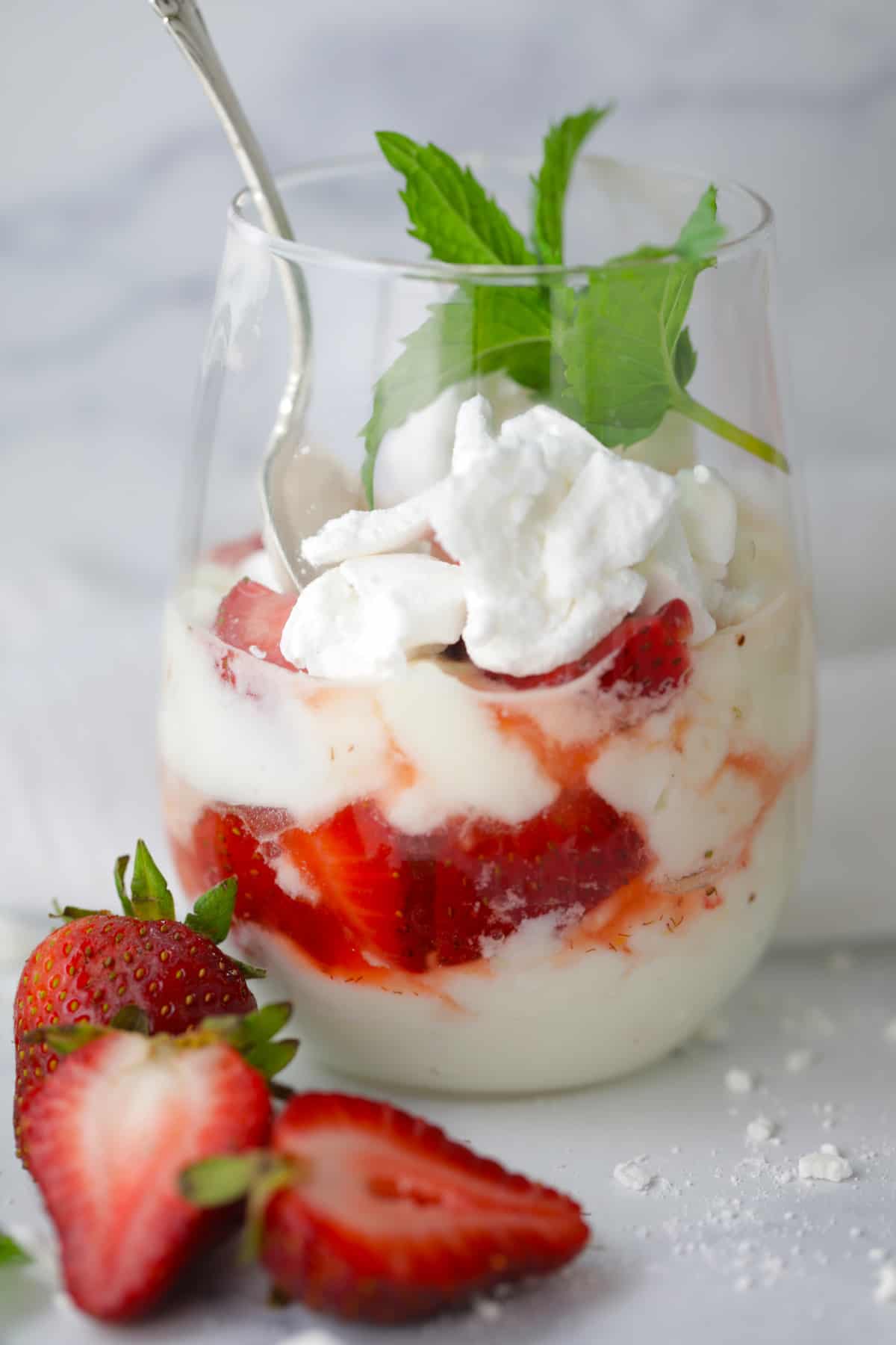 One stemless wine glass filled with the English trifle dessert with fresh mint on top.