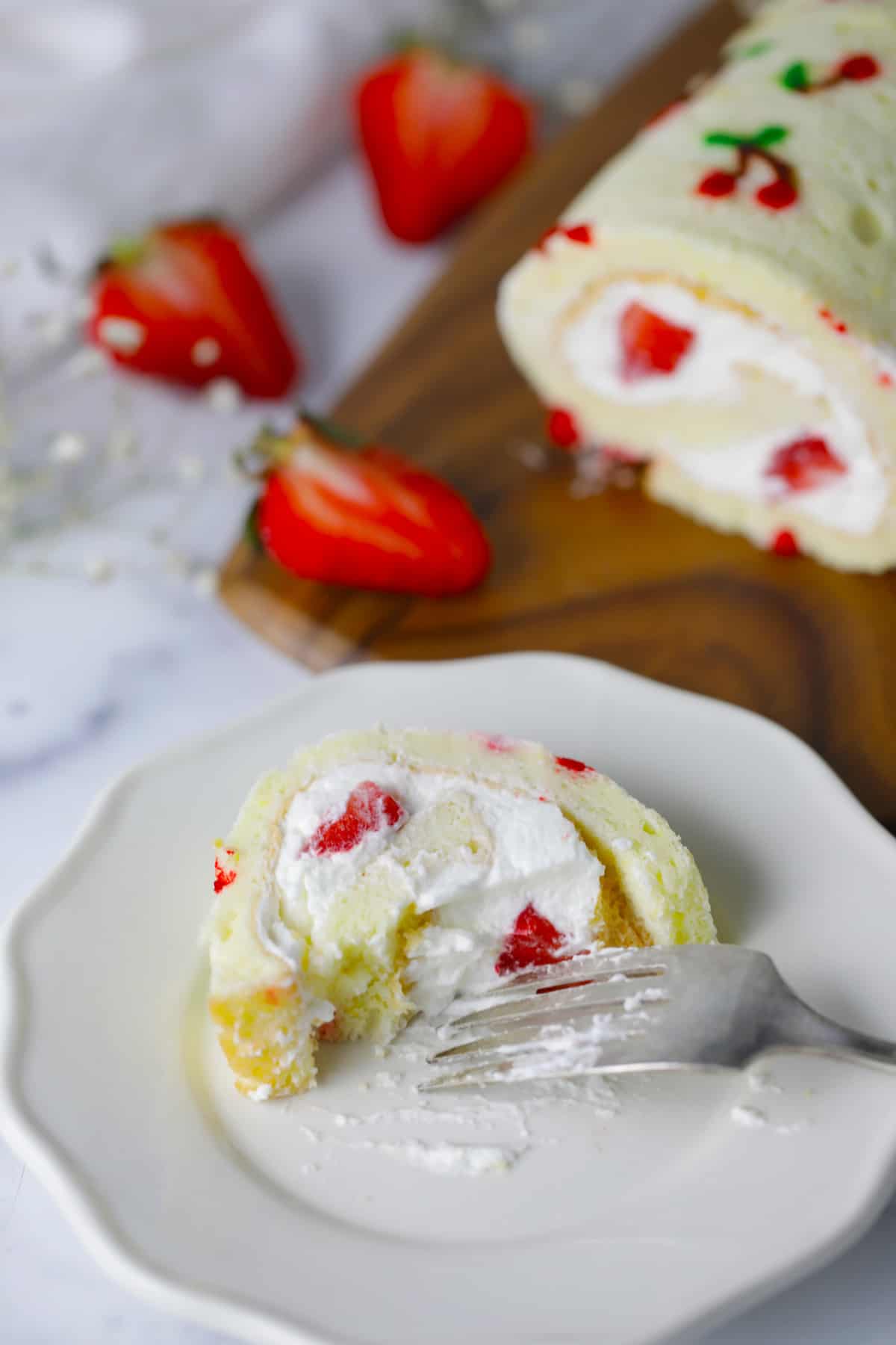 White plate with slice of cake roll which has been half eaten.