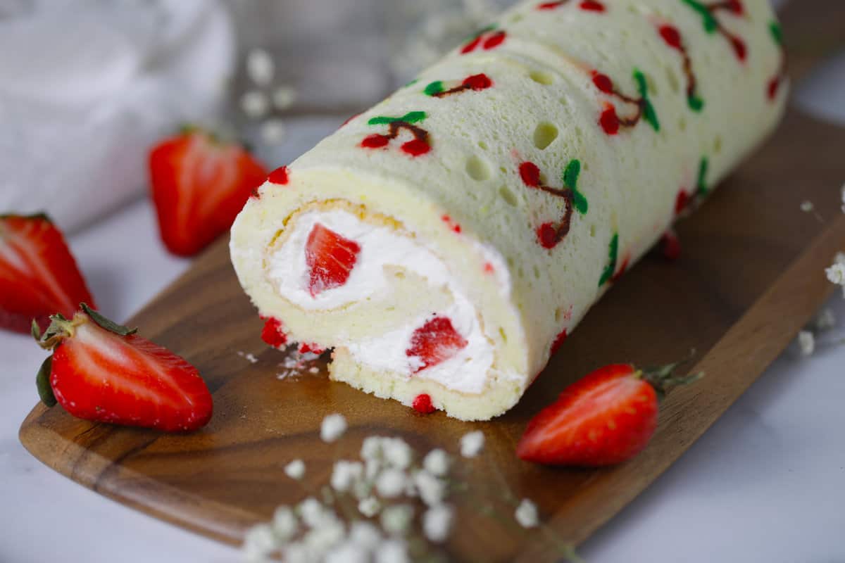 Vanilla cake roll with cherries pattern made of colored cake batter.