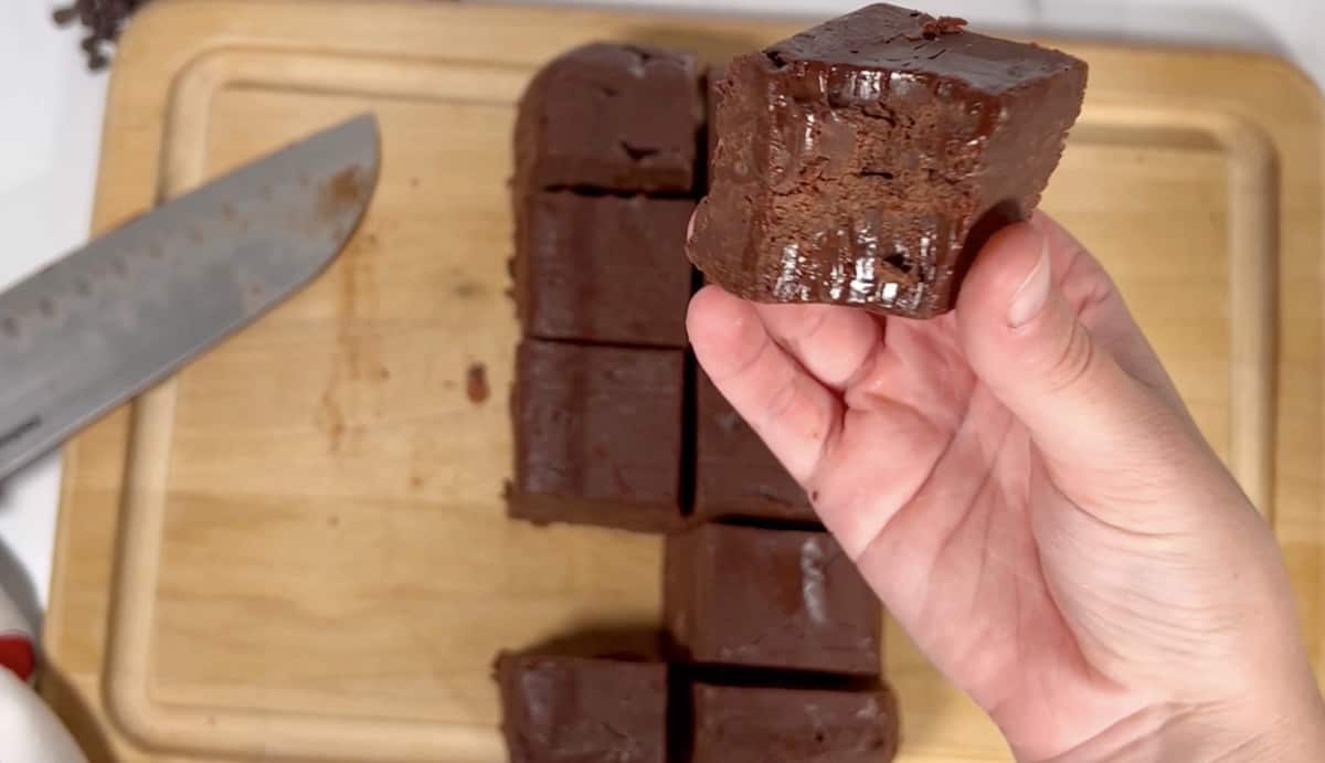 Cutting board with knife on side and freshly cut pieces of fudge on board.