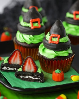 Chocolate covered strawberry witch hat cupcakes on a black plate and green napkin.