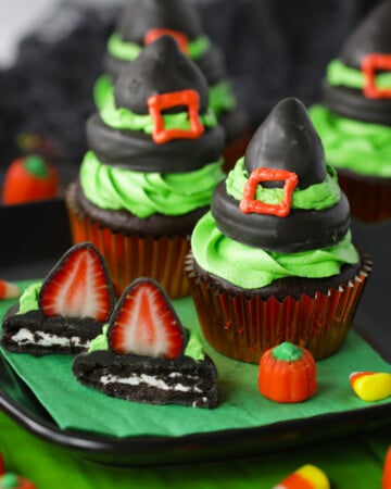 Chocolate covered strawberry witch hat cupcakes on a black plate and green napkin.