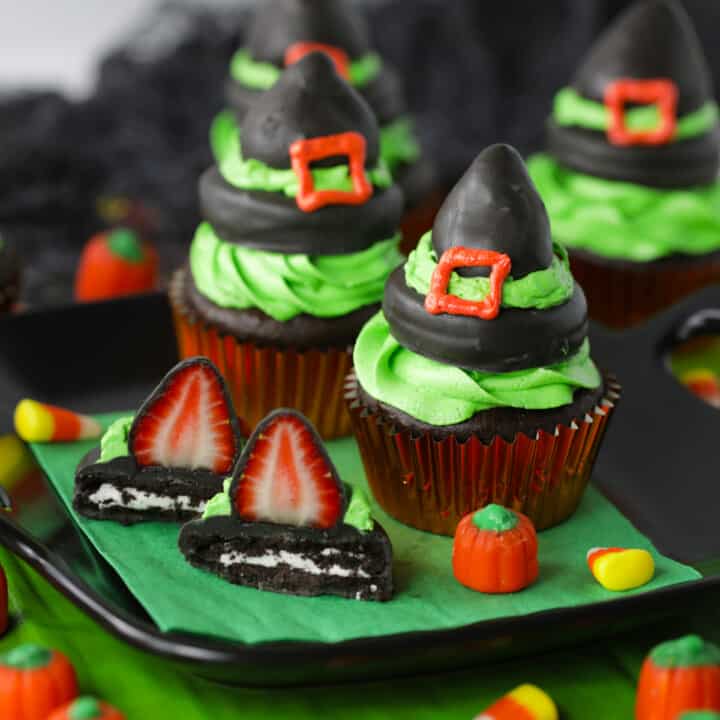 Chocolate covered strawberry witch hat cupcakes on a black plate and green napkin.