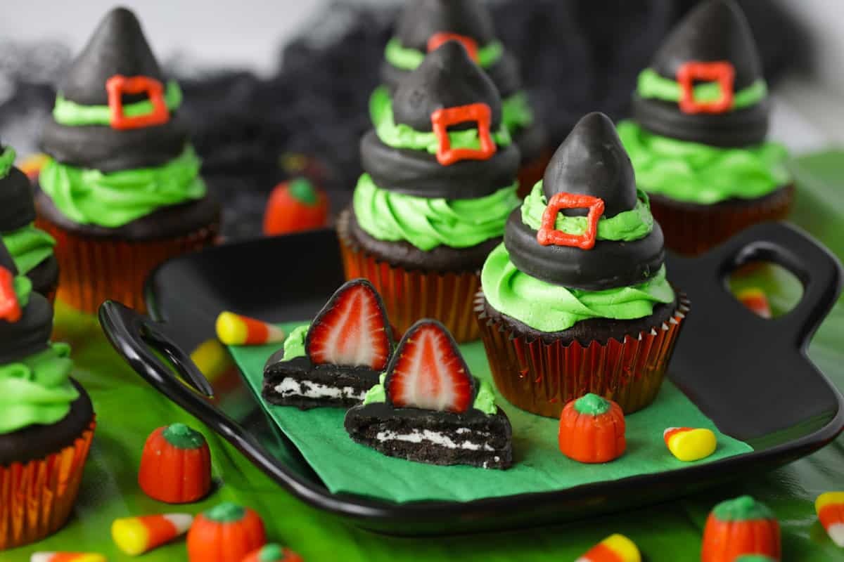 Black plate with two cupcakes decorated with chocolate witch hats.