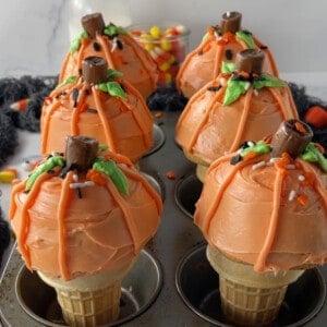 Muffin pan with six pumpkin ice cream cone cupcakes in it.