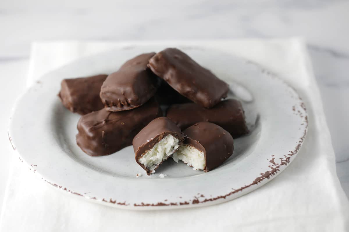 Chocolate covered coconut bars on a white plate.