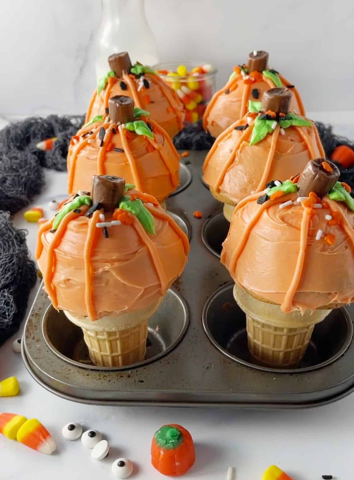 Six Ice cream cone cupcakes that have been frosted and decorated in muffin pan.