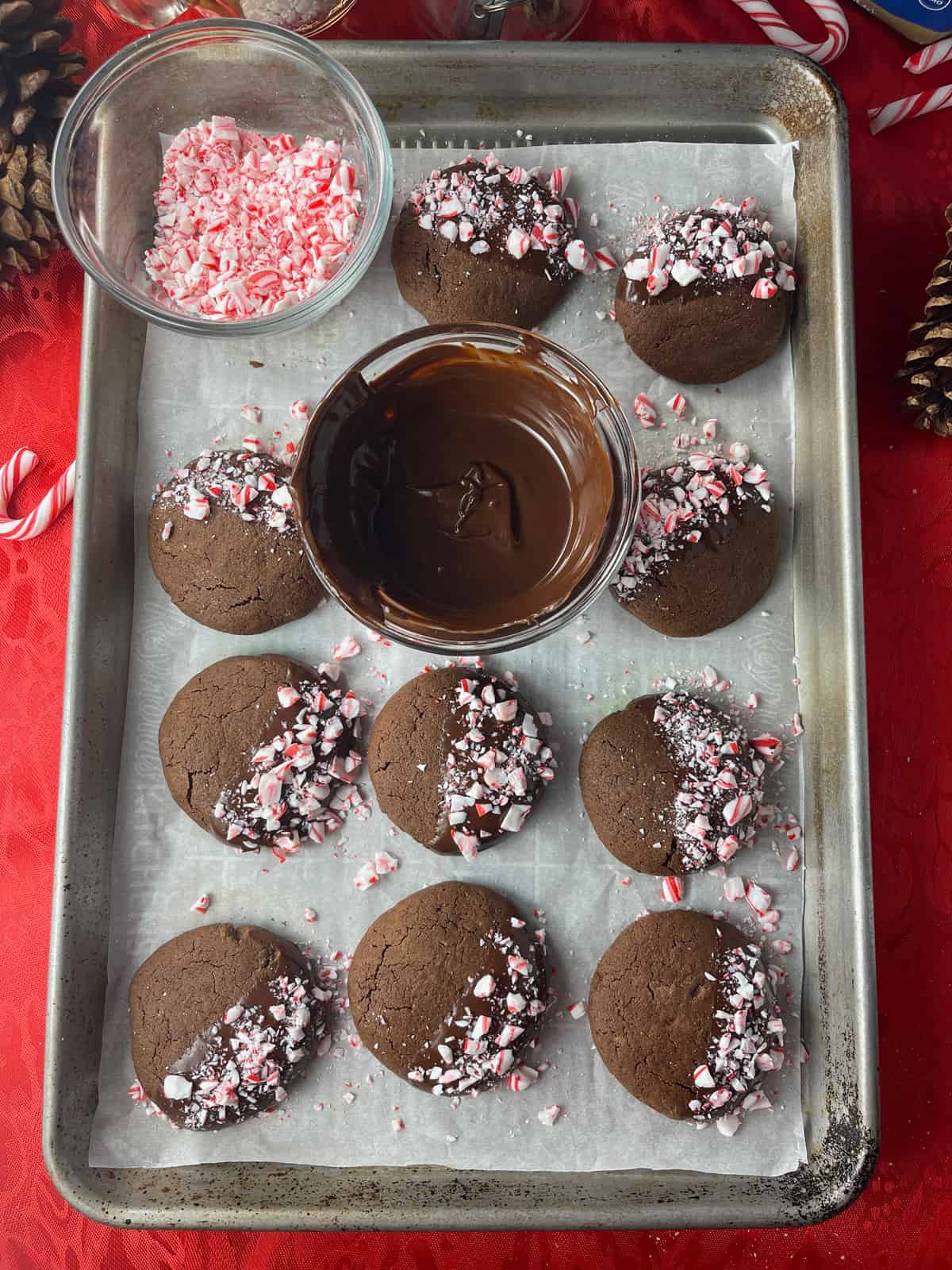 Cookies dipped in melted chocolate and drying on a parchment lined cookie sheet.