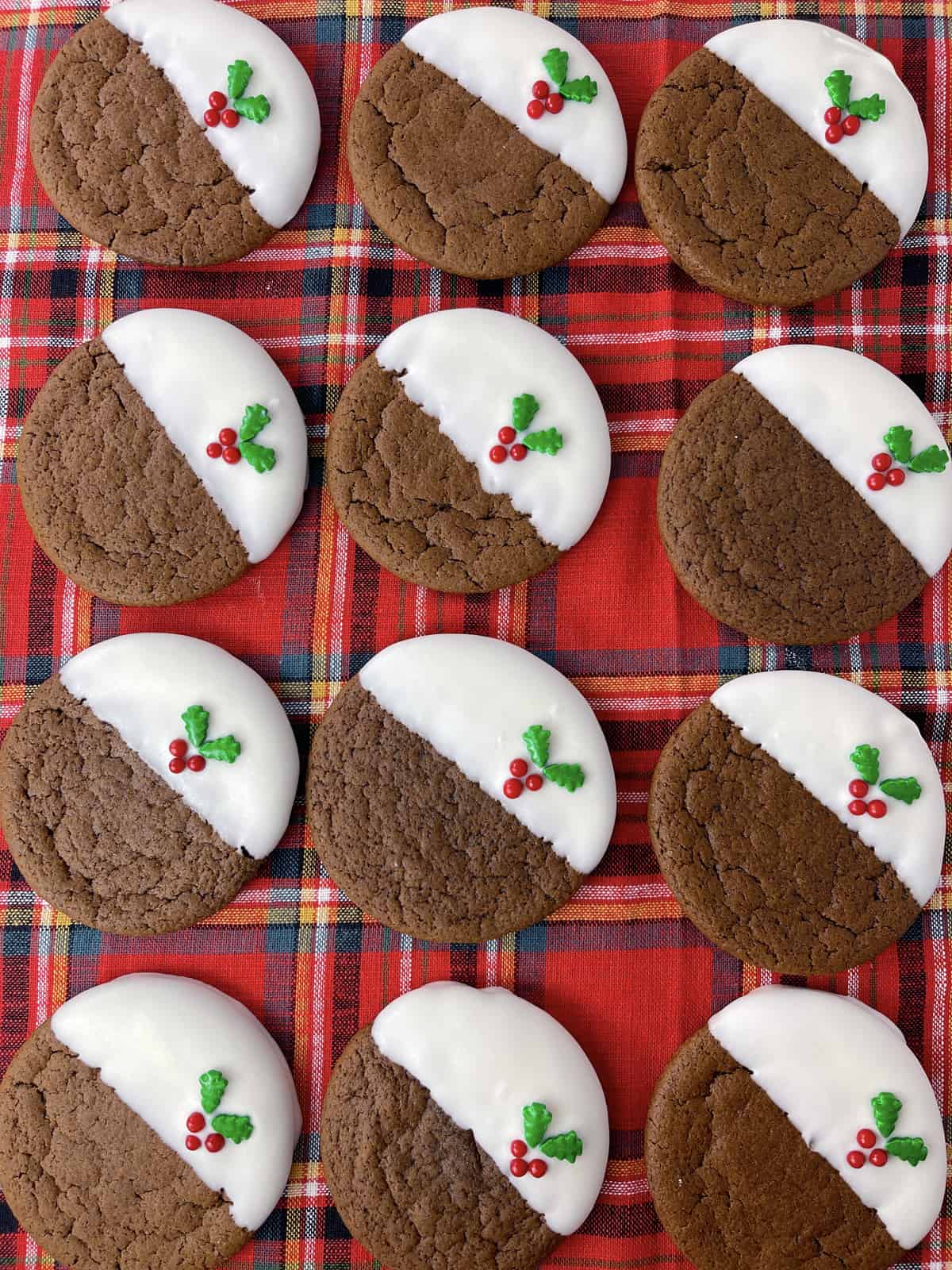 Four rows of pretty ginger cookies on a red plaid cloth.